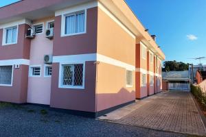um edifício cor-de-rosa e laranja com um passadiço de tijolos em RCM Vilas - STUDIO n 14 em Joinville