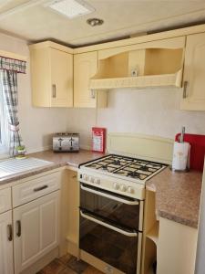 a kitchen with white cabinets and a stove top oven at Warden spring in Leysdown-on-Sea