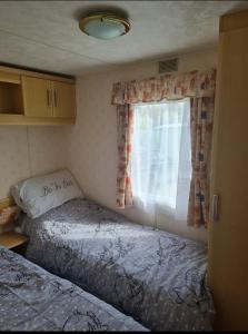 - 2 lits dans une petite chambre avec fenêtre dans l'établissement Warden spring, à Leysdown-on-Sea