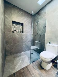 a bathroom with a toilet and a glass shower at Estudio Colibrí MID - Centro Histórico Mérida in Mérida