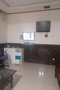 a living room with a tv on a wall at OYO 93101 Al-ainah Family Homestay in Medan