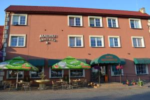 a building with tables and umbrellas in front of it at Malibu Kalisz in Kościelna Wieś