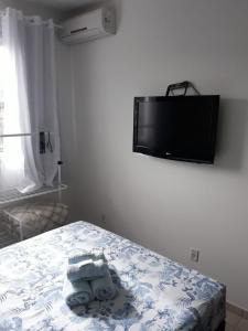 a bedroom with a bed with towels and a tv on the wall at RCM Vilas - STUDIO n18 in Joinville