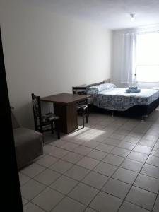 a room with two beds and a desk and a chair at RCM Vilas - STUDIO n18 in Joinville