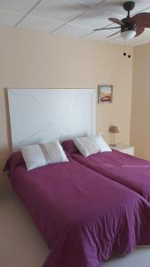 a bedroom with two beds with purple sheets and a ceiling at Hotel Rural-Restaurante Los Olivos in Almería