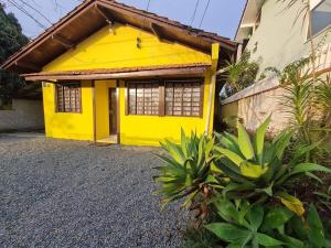 uma casa amarela com uma porta amarela e algumas plantas em RCM Vilas - YELLOW HOUSE em Joinville