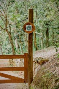 un poteau en bois avec une horloge dans les bois dans l'établissement Reserva Atibaia / Casa de Montanha, à Atibaia