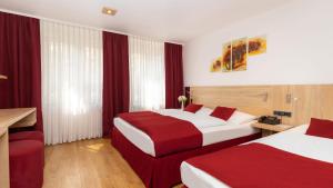2 Betten in einem Hotelzimmer in Rot und Weiß in der Unterkunft LeoMar Hotel in Ulm