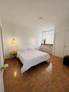 een slaapkamer met een groot wit bed en een houten vloer bij Apartamento en el poblado in Medellín