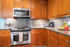 a kitchen with wooden cabinets and a stove and microwave at Mauna Lani Fairways 1101 in Waikoloa