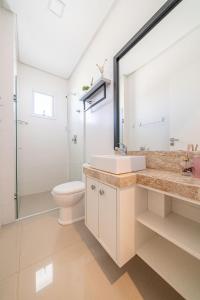 a bathroom with a sink and a toilet and a mirror at Edifício Costa Brava em Canto Grande Bombinhas in Bombinhas