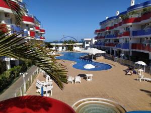 una piscina con sillas y sombrillas junto a un edificio en Maravilhoso apto wi-fi e vista para o mar - HB06F, en Florianópolis