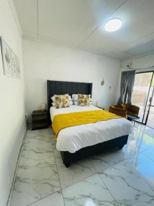 a bedroom with a large bed with a yellow blanket at The Bliss Boutique in Louis Trichardt