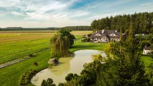 an aerial view of a house in a field with a pond at Hubertus Dwór Myśliwski in Opole