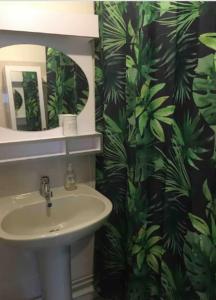 a bathroom with a sink and a green leafy shower curtain at New Port in Saint-Cast-le-Guildo