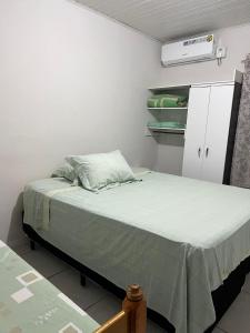 a small bedroom with a bed with a green blanket at Residencial Coração do Mar in Palhoça