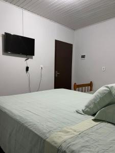 a bedroom with a bed with a flat screen tv on the wall at Residencial Coração do Mar in Palhoça