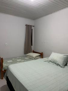 a small bedroom with a bed and a window at Residencial Coração do Mar in Palhoça