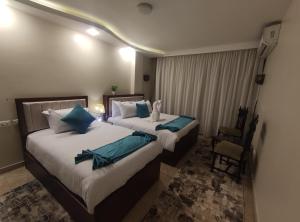 a hotel room with two beds and a chair at Diamond Pyramids View Apartment in Cairo