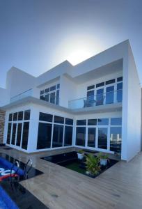 una gran casa blanca con una piscina frente a ella en bh villa en Al Ashkharah