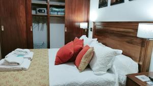 a bedroom with a bed with red and white pillows at Los Tres Lapachos "Orange" in Salta