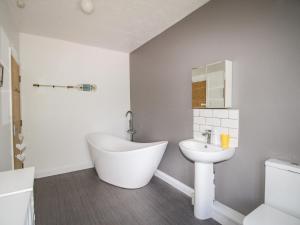 a bathroom with a white tub and a sink at The White Cottage in Weymouth