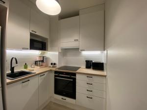 a white kitchen with white cabinets and a sink at Funky City Apartment in Rovaniemi