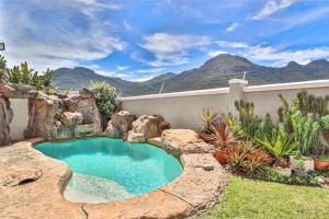 a swimming pool in a garden with mountains in the background at Apartments Hout Bay in Cape Town