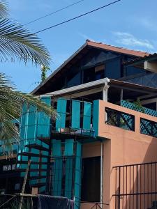 un edificio con ventanas azules y una palmera en Uverito Sand Dollar B&B en Las Tablas