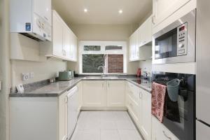 a white kitchen with white cabinets and a window at Home from Home 4 Bed - Ideal for Workers & Great for Groups, FREE Parking, Spacious, Pet Friendly Netflix in Kimberworth
