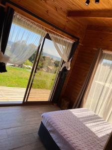 a bedroom with a bed and a large window at Cabañas Luz de Luna, Playa Curanipe in Curanipe