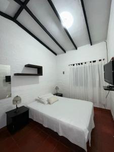 ein weißes Schlafzimmer mit einem Bett und einem TV in der Unterkunft Rancho 4Js in La Cumbre