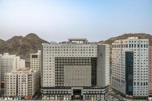 un groupe de grands bâtiments avec des montagnes en arrière-plan dans l'établissement Elaf Bakkah Hotel, à La Mecque
