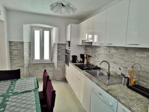 a kitchen with white cabinets and a sink and a table at Holiday home Kastel Stari in Kaštela