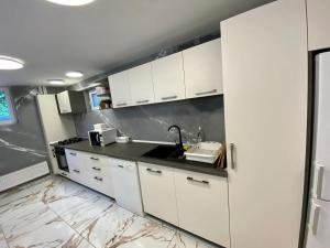a kitchen with white cabinets and a sink at Pensiunea Arinul in Sovata