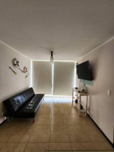 ein Wohnzimmer mit einem schwarzen Sofa und einem TV in der Unterkunft Departamento Los Molles, Exclusivo Frente a el Mar in Los Molles