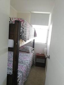 ein kleines Schlafzimmer mit einem Etagenbett und einem Fenster in der Unterkunft Departamento Los Molles, Exclusivo Frente a el Mar in Los Molles