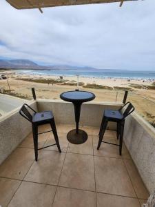 einen Tisch und zwei Stühle auf einem Balkon mit Strand in der Unterkunft Departamento Los Molles, Exclusivo Frente a el Mar in Los Molles