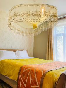 - une chambre avec un lit jaune et un lustre dans l'établissement Keitylin Heights Apartments in Makindye, à Kampala