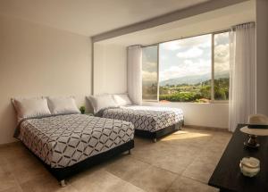 a bedroom with two beds and a large window at Apartamento Campestre en Condominio in Fusagasuga