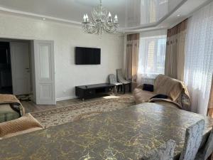 sala de estar con mesa y TV en Уютная квартира комфорт класса - 41, en Astana