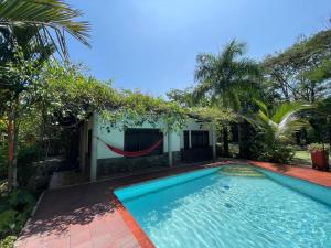una piscina con amaca di fronte a una casa di Catleya Cabaña Campestre a Villavicencio