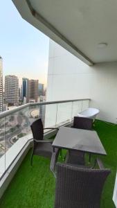 a table and chairs on a balcony with green grass at Near Atana Hotel in Dubai