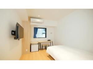 Un dormitorio con una cama y una mesa y una ventana. en ELE HOTEL KUZUHA- Vacation STAY 80313v, en Hirakata