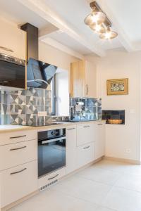een keuken met witte kasten en een fornuis met oven bij Gîtes dans un mas en pierres au coeur d'un domaine viticole du Pic Saint-Loup in Corconne