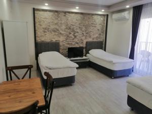 Cette chambre comprend 3 lits, un bureau et une table. dans l'établissement SKY HOTEL & APARTMENTS, à Antalya