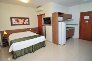 a hotel room with a bed and a refrigerator at My Flat in Mogi das Cruzes