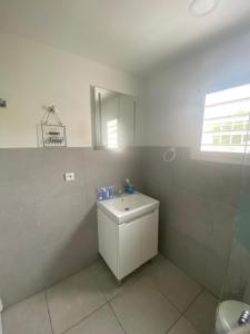 a white bathroom with a sink and a mirror at Akunamatata Guest House Grand Case in Grand Case