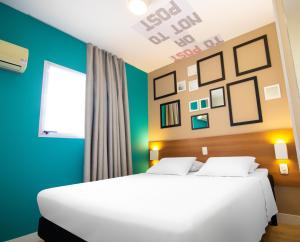 a bedroom with a white bed and a blue wall at Hotel Dan Inn São Carlos By Nacional Inn in São Carlos