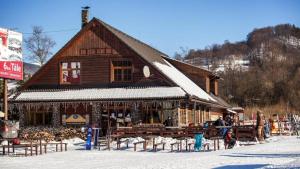 a large wooden building with people standing outside in the snow at Chalet Fiona with jacuzzi in Mýto pod Ďumbierom